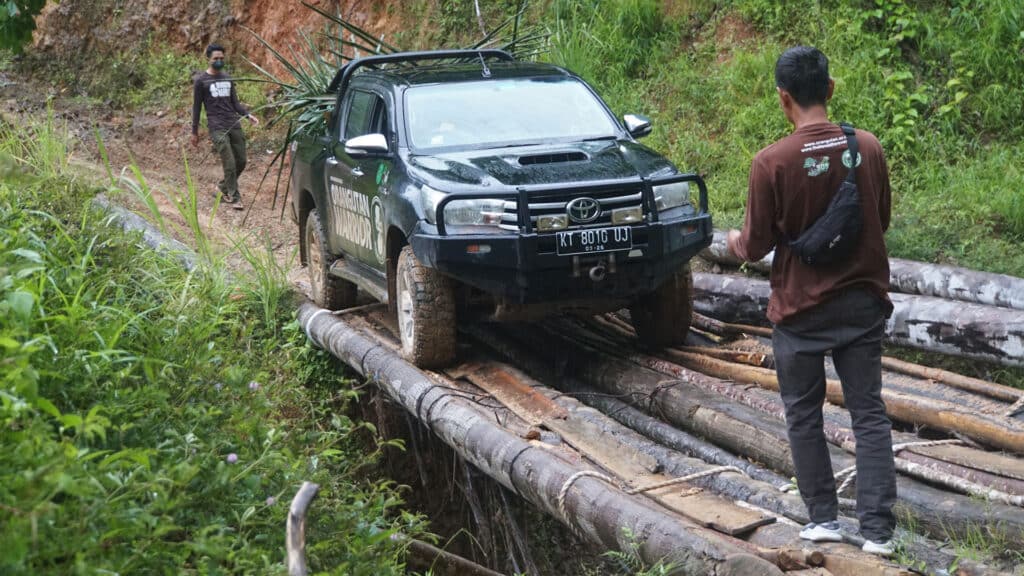 Ein Jeep fährt über eine halb zerstörte Holzbrücke